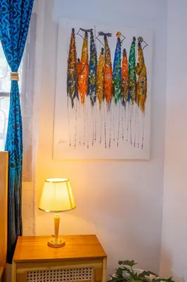 a lamp on a table next to a painting of colorful fish at Noric Homes and Adventure in Msaranga