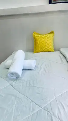 a white bed with a yellow pillow and white sheets at Osim Lodge City Centre in Arusha