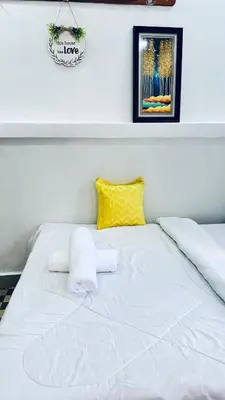 a white bed with a yellow pillow on it at Osim Lodge City Centre in Arusha