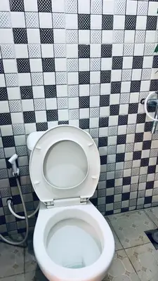 a bathroom with a toilet with a black and white tiled wall at Osim Lodge City Centre in Arusha
