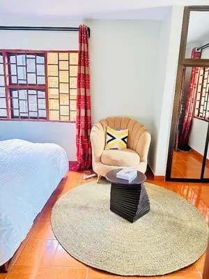 a bedroom with a bed and a chair and a table at KL shadow Homes in Arusha