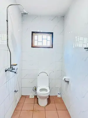 a white bathroom with a toilet and a window at KL shadow Homes in Arusha