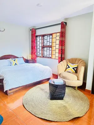 a bedroom with a bed and a chair and a rug at KL shadow Homes in Arusha
