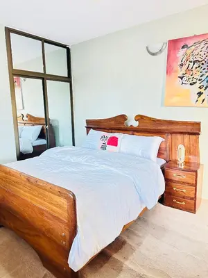 a bedroom with a wooden bed and a mirror at KL shadow Homes in Arusha