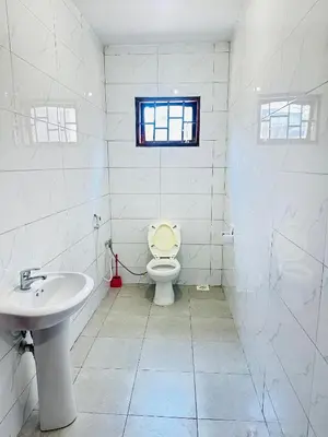 a bathroom with a toilet and a sink and a window at KL shadow Homes in Arusha