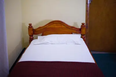 a bed with a wooden headboard in a room at New Siesta Inn in Nkunjila
