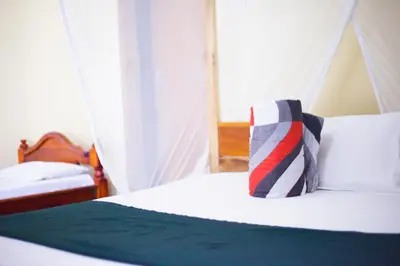 a bedroom with a bed with a striped pillow on it at New Siesta Inn in Nkunjila