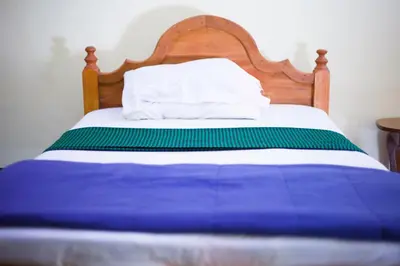 a blue and white bed with a wooden head board at New Siesta Inn in Nkunjila
