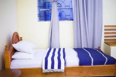 a bed with a blue and white blanket and a window at New Siesta Inn in Nkunjila