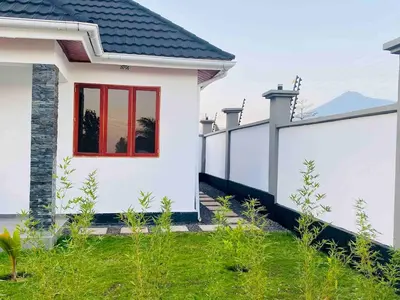 a white house with a red window in a yard at Small White House Njiro in Arusha