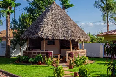 a hut with a grass roof in a yard at Sisama Lodge in Msaranga