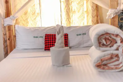 a bedroom with a bed with two towels on it at Sisama Lodge in Msaranga