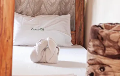 a towel sitting on top of a bed with a pillow at Sisama Lodge in Msaranga
