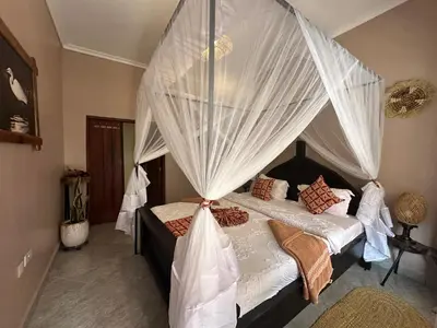 a bedroom with a canopy bed with white curtains at Meru Nest Arusha Bed & Breakfast in Arusha