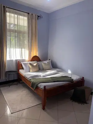 a bed sitting in a room with a window at Wimake homes in Arusha