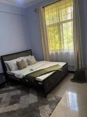 a bed sitting in a room with a window at Wimake homes in Arusha