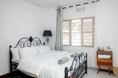 a bedroom with a black and white bed and a window at The Manor Garden House - Arusha Eight-Minute City Stay in Arusha