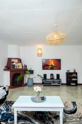 a living room with a table and a fireplace at The Manor Garden House - Arusha Eight-Minute City Stay in Arusha