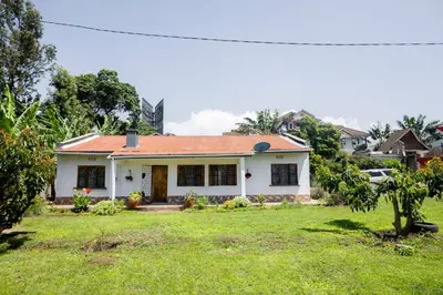 a white house with an orange roof on a yard at The Manor Garden House - Arusha Eight-Minute City Stay in Arusha