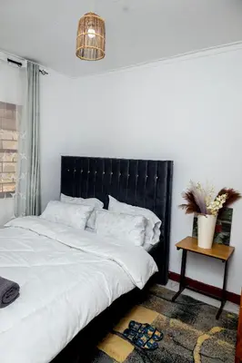 a bed with a black headboard in a bedroom at The Manor Garden House - Arusha Eight-Minute City Stay in Arusha