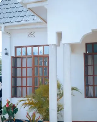 a white house with red windows and plants at Arusha Oasis Executive Residence in Arusha