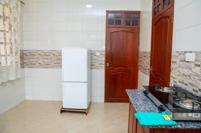 a kitchen with a white refrigerator and a wooden door at Arusha Oasis Executive Residence in Arusha