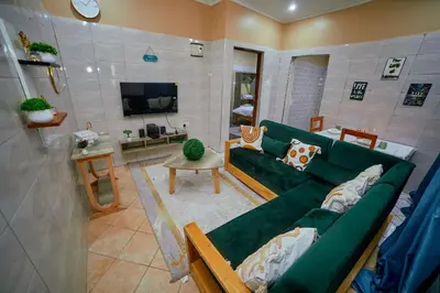 a living room with a green couch and a tv at Zaal stays in Arusha