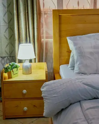 a bedroom with a bed and a night stand with a lamp at Zaal stays in Arusha