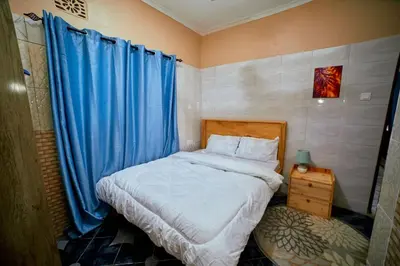 a small bedroom with a bed with blue curtains at Zaal stays in Arusha