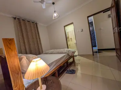 a bedroom with a bed with a lamp and a mirror at Joy Land Stay in Arusha
