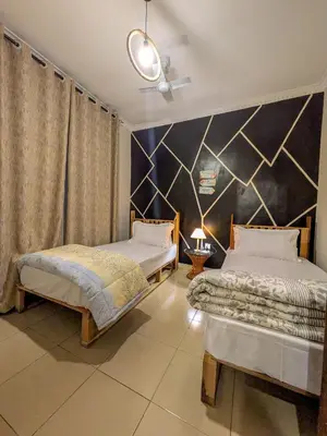 a bedroom with two beds and a black wall at Joy Land Stay in Arusha