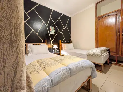 a bedroom with two beds and a black wall at Joy Land Stay in Arusha