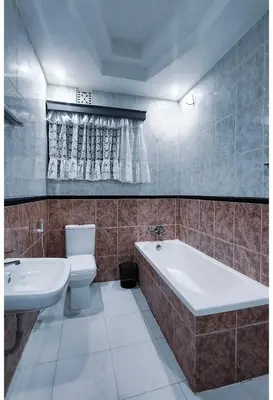 a bathroom with a tub and a toilet and a sink at Sunset Quarters in Arusha