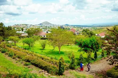 two people walking down a dirt road in a field at Kitopua suites in Arusha