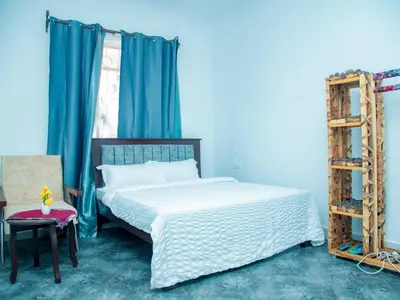 a bedroom with a bed with blue walls and a ladder at Serene Vacay Lodge Soweto in Moshi