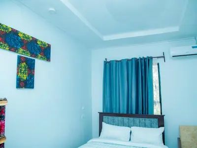 a bedroom with blue walls and a bed and a window at Serene Vacay Lodge Soweto in Moshi
