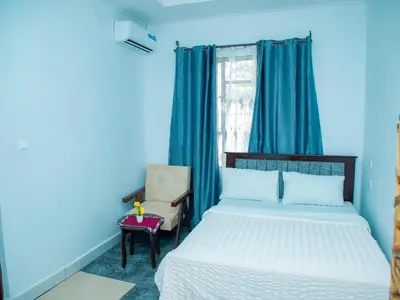 a blue bedroom with a bed and a chair at Serene Vacay Lodge Soweto in Moshi