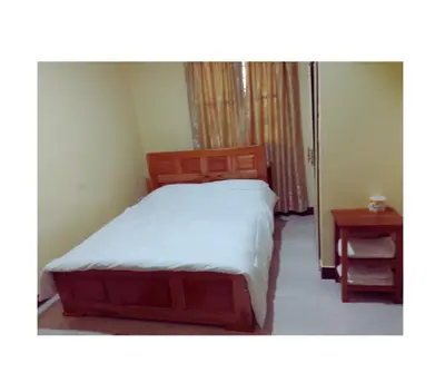 a small bedroom with a bed and a table at Moshi Roots Homestay in Msaranga