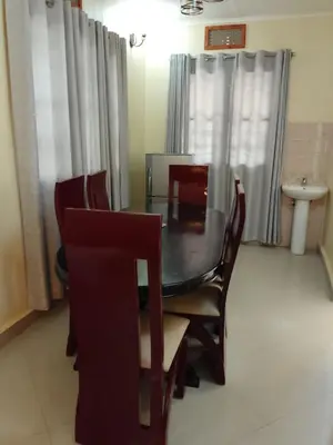 a dining room with a glass table and chairs at Moshi Roots Homestay in Msaranga
