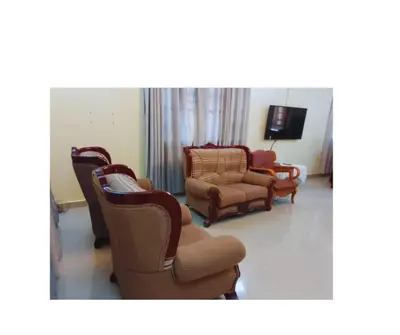 a living room with chairs and a couch and a tv at Moshi Roots Homestay in Msaranga