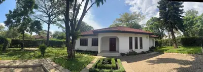 a small white house in the middle of a yard at Arusha Njiro B&B in Arusha