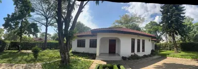 a small white house in the middle of a yard at Arusha Njiro B&B in Arusha