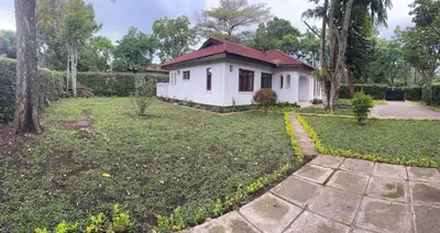 a white house with a red roof in a yard at Arusha Njiro B&B in Arusha