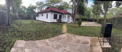 a small white house in the middle of a yard at Arusha Njiro B&B in Arusha