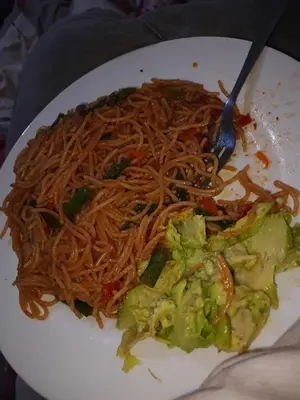a plate of spaghetti and vegetables with a fork at Karibu Neema Homestay and Breakfast in Nkoanrua