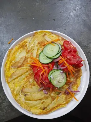 a omelet with vegetables on a white plate at Karibu Neema Homestay and Breakfast in Nkoanrua
