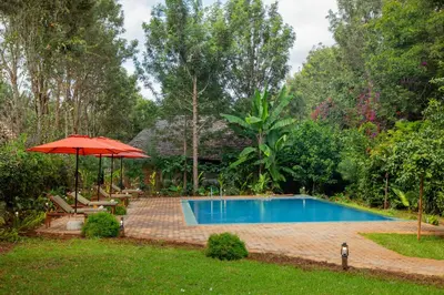 a swimming pool with a red umbrella and chairs and a table and an umbrella at Njiapanda Tented Lodge & Safari in Karatu