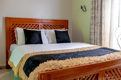 a bedroom with a large wooden bed with black and white pillows at Subira Home in Arusha