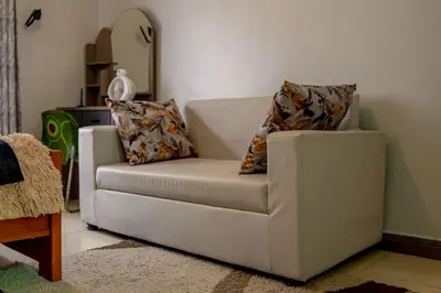 a white couch with two pillows on it in a living room at Subira Home in Arusha