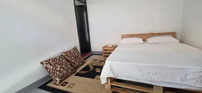 a bedroom with a bed and a chair in it at Ruby Cozy Home's in Arusha